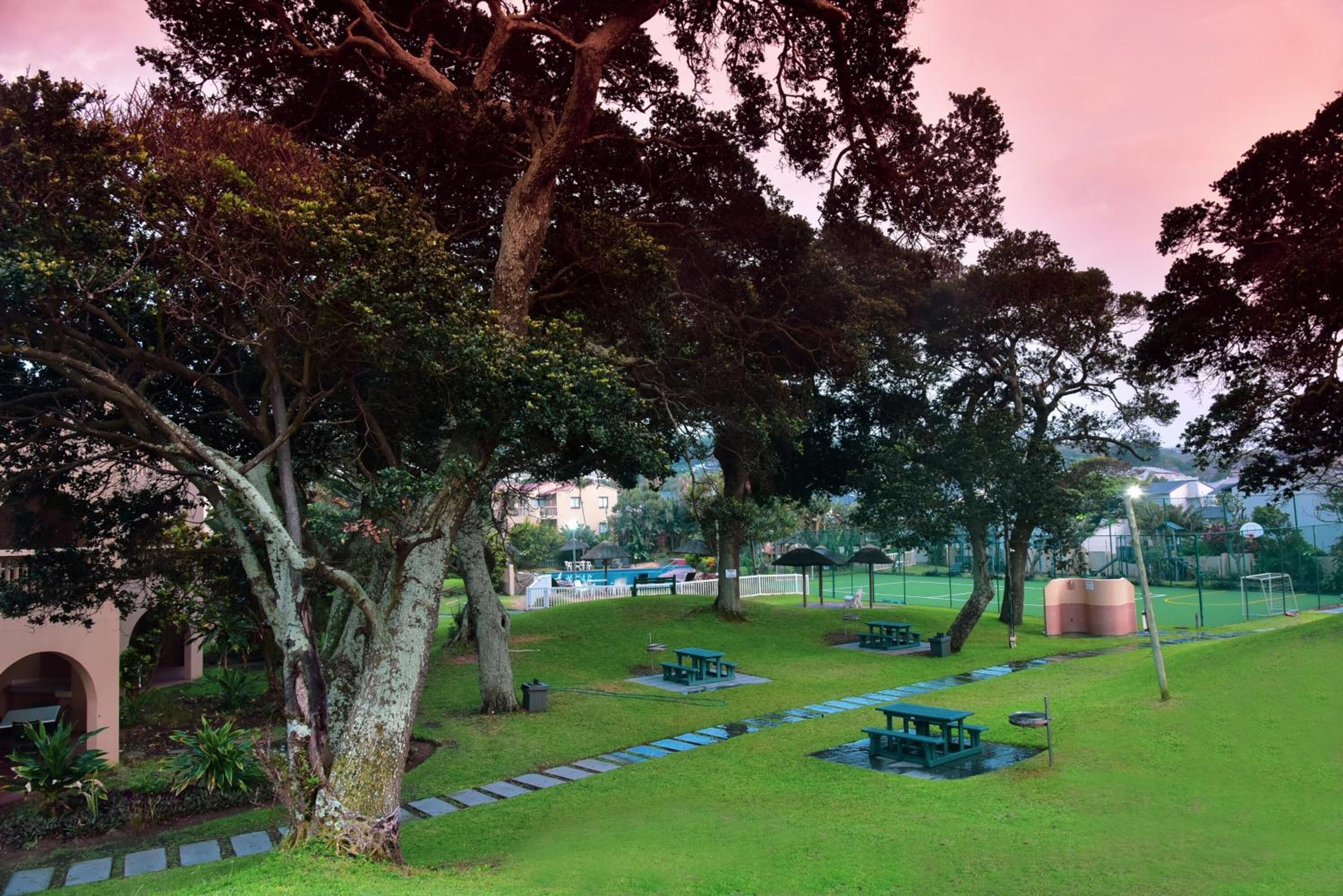 A park with picnic tables, a walking path, and trees.