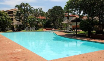 Una piscina al aire libre, sillones reclinables de piscina