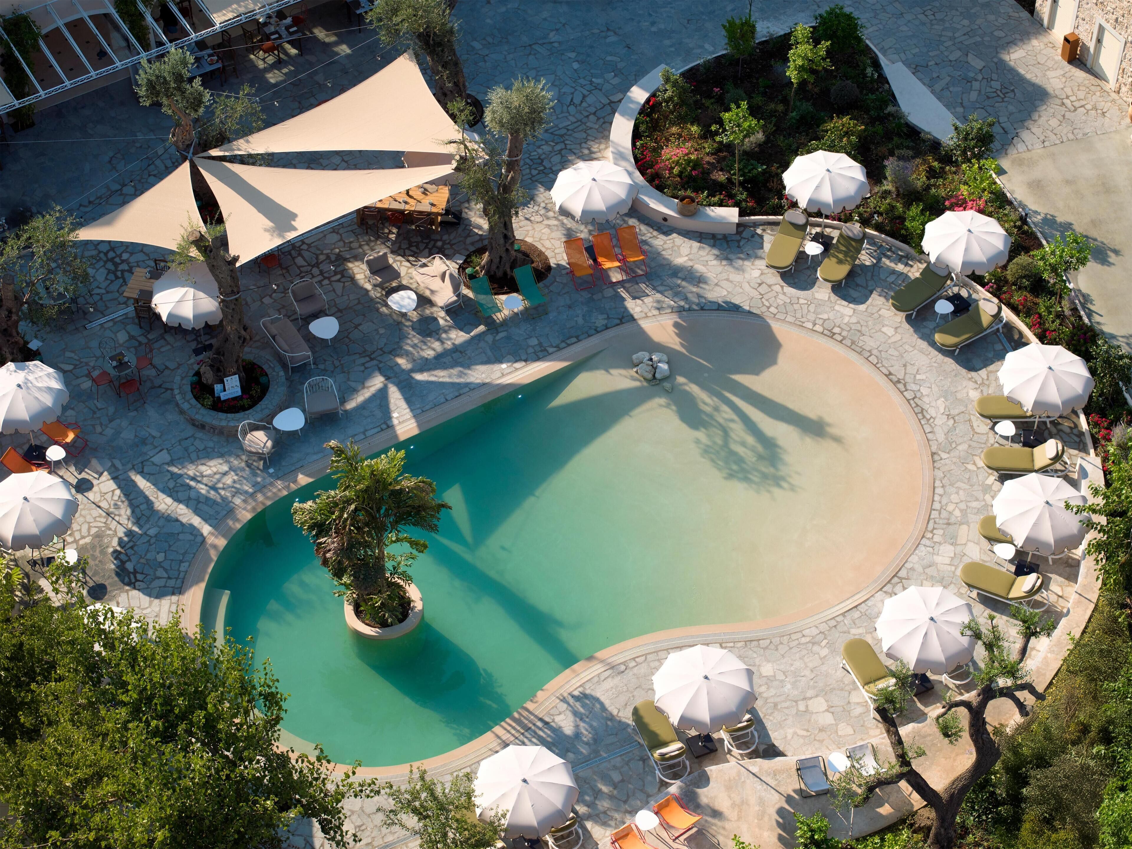Ein Luftbild eines Resorts mit Schwimmbad, Liegestühlen und Außenbereich-Sitzgelegenheiten.