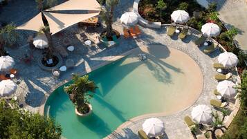 Ein Luftbild eines Resorts mit Schwimmbad, Liegestühlen und Außenbereich-Sitzgelegenheiten.