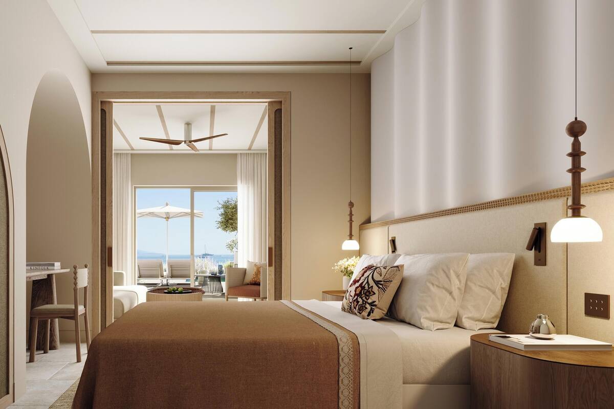 A spacious bedroom with a large bed, a sitting area with a view, and a ceiling fan.