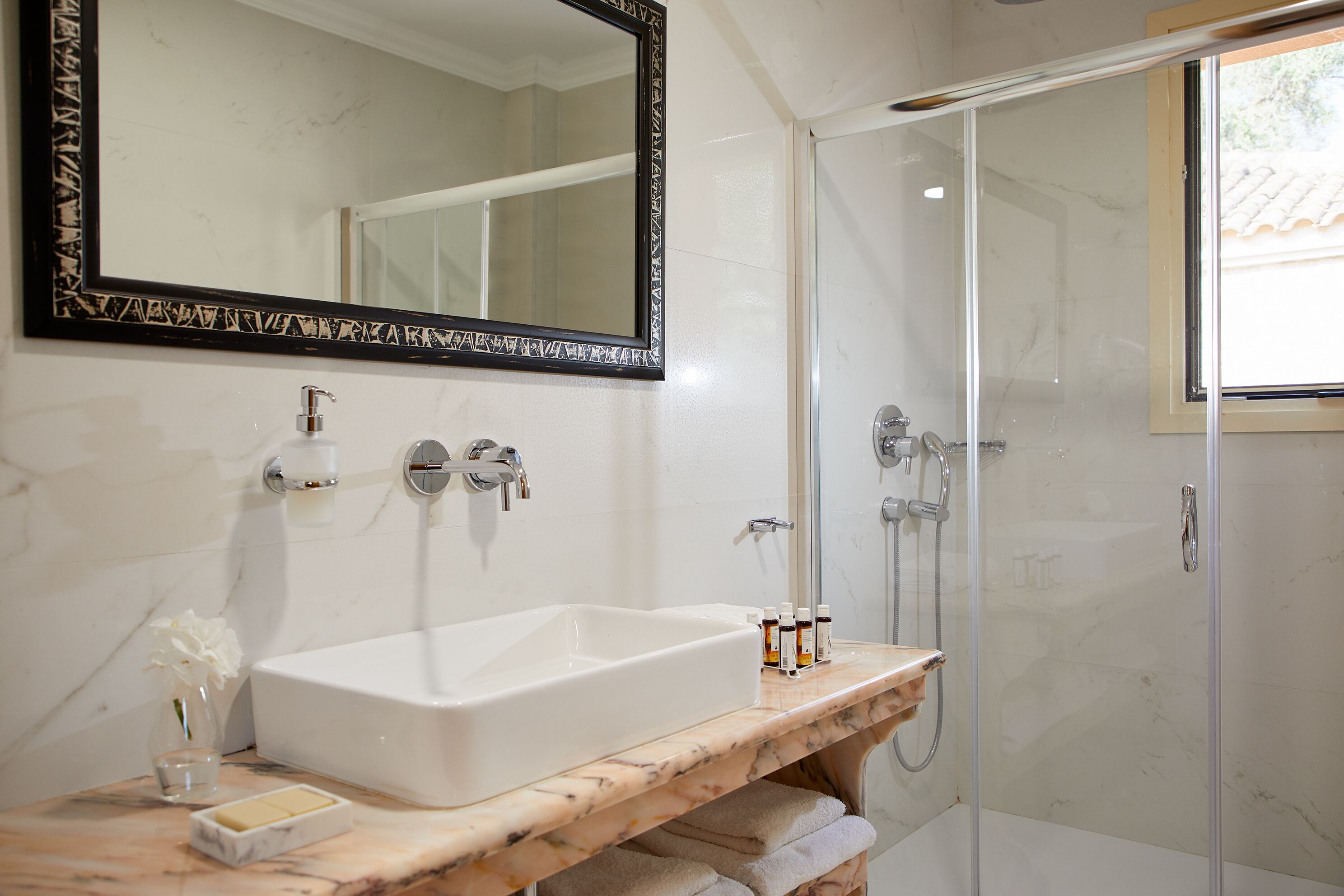 A bathroom with a white sink, mirror, and shower.