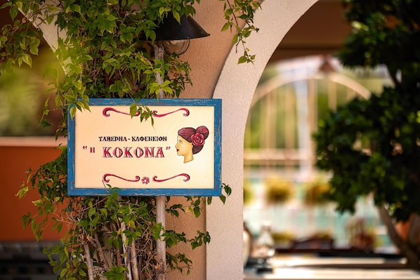 A vintage sign with text and a woman's profile, surrounded by greenery.