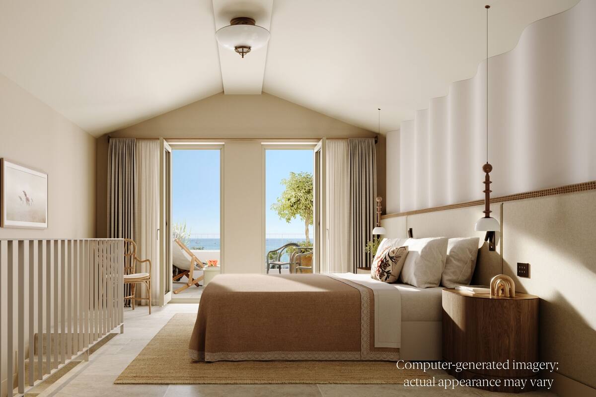 A bedroom with a large bed, a view of the sea, and a window with curtains.