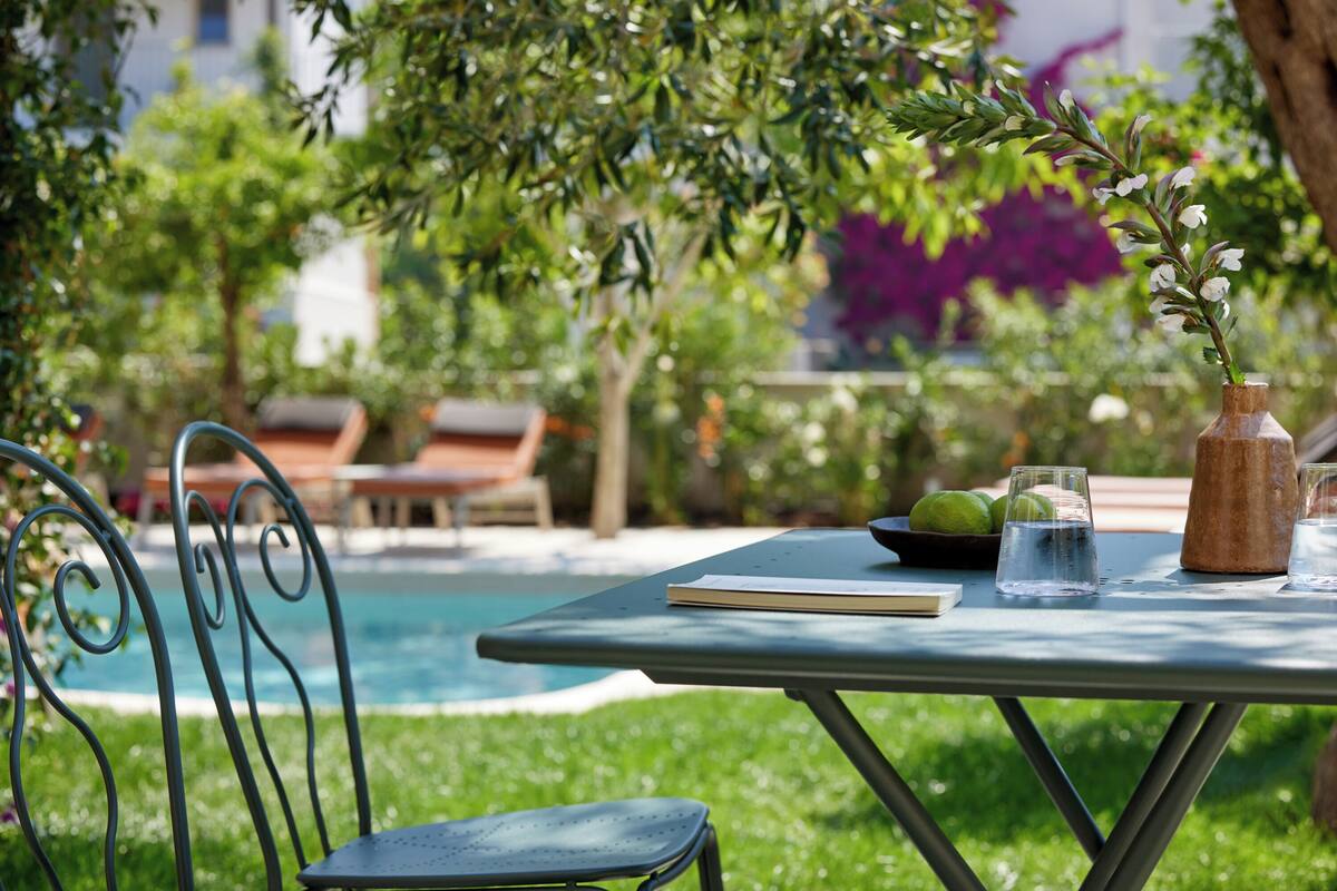 A poolside table with a book, a vase with flowers, and glasses of water.