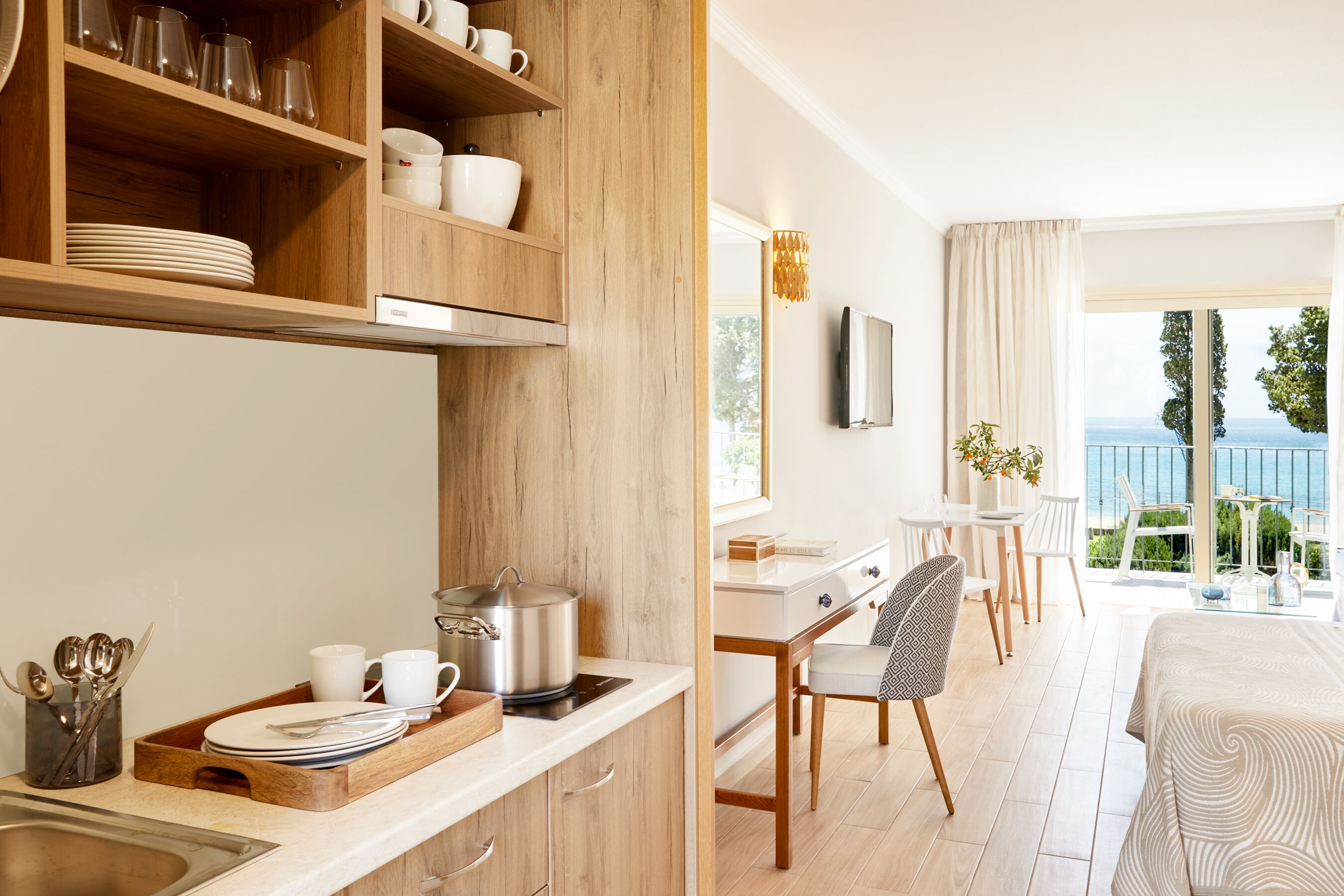 Une chambre d’hôtel moderne dotée d’un coin cuisine, d’un espace repas et d’un balcon avec vue.