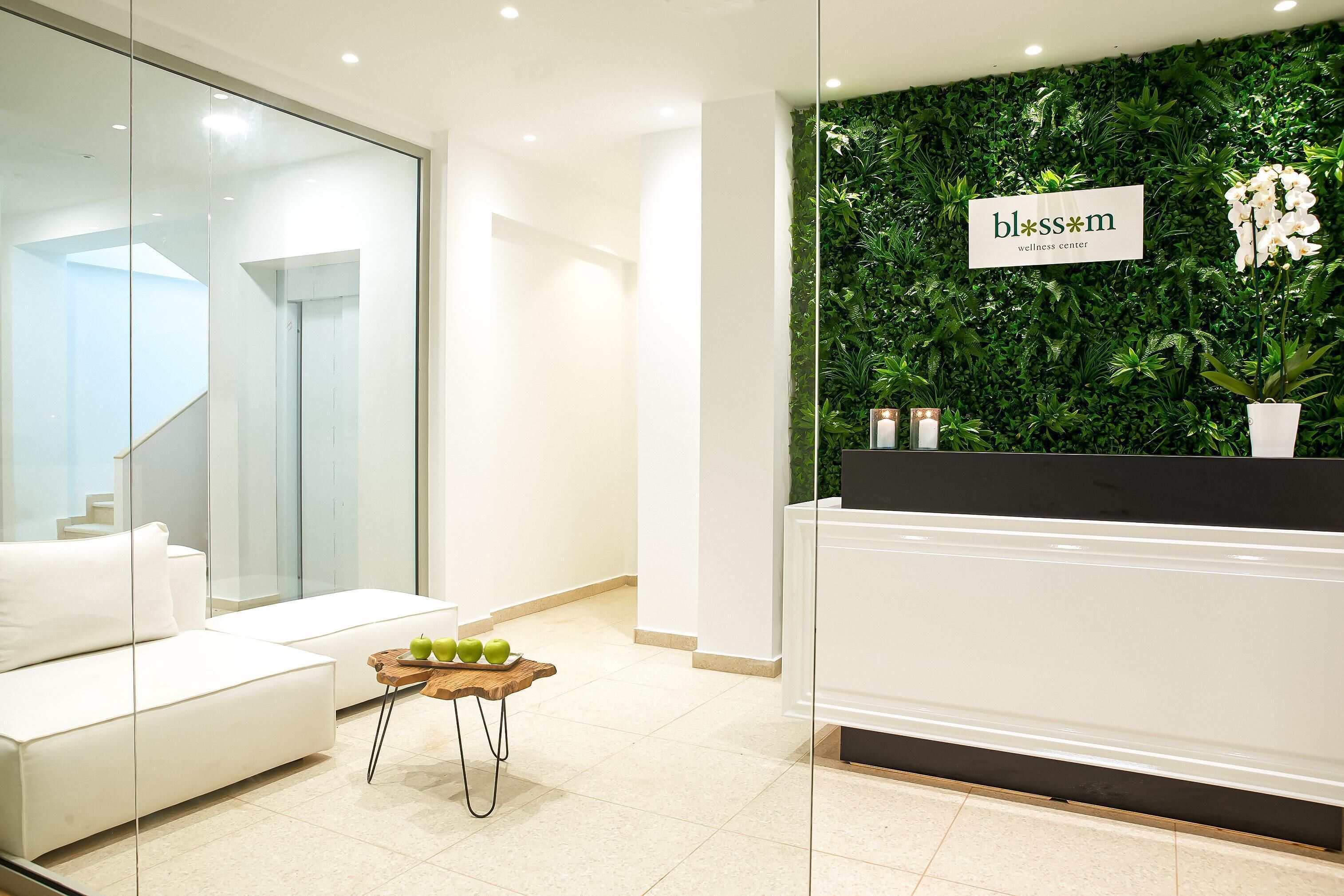 Un área de recepción con una pared verde, un mostrador blanco y un sofá blanco.