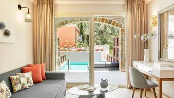 A modern living room with a sofa, a glass coffee table, a desk, and a view of an outdoor pool area.