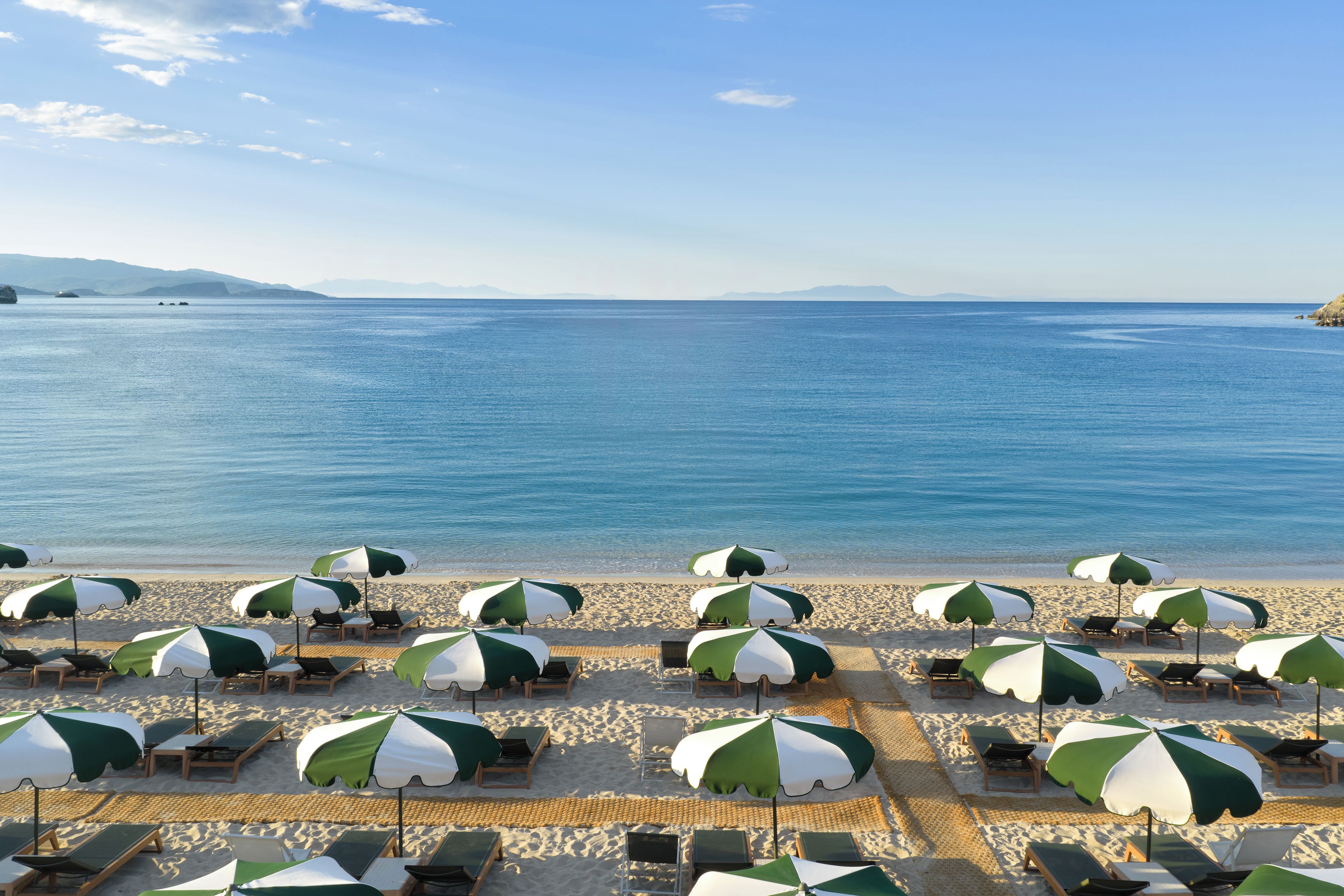 A beach with rows of sun loungers and umbrellas.