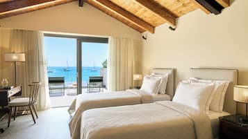 Habitación de hotel con dos camas, un escritorio, una silla y vista al mar.