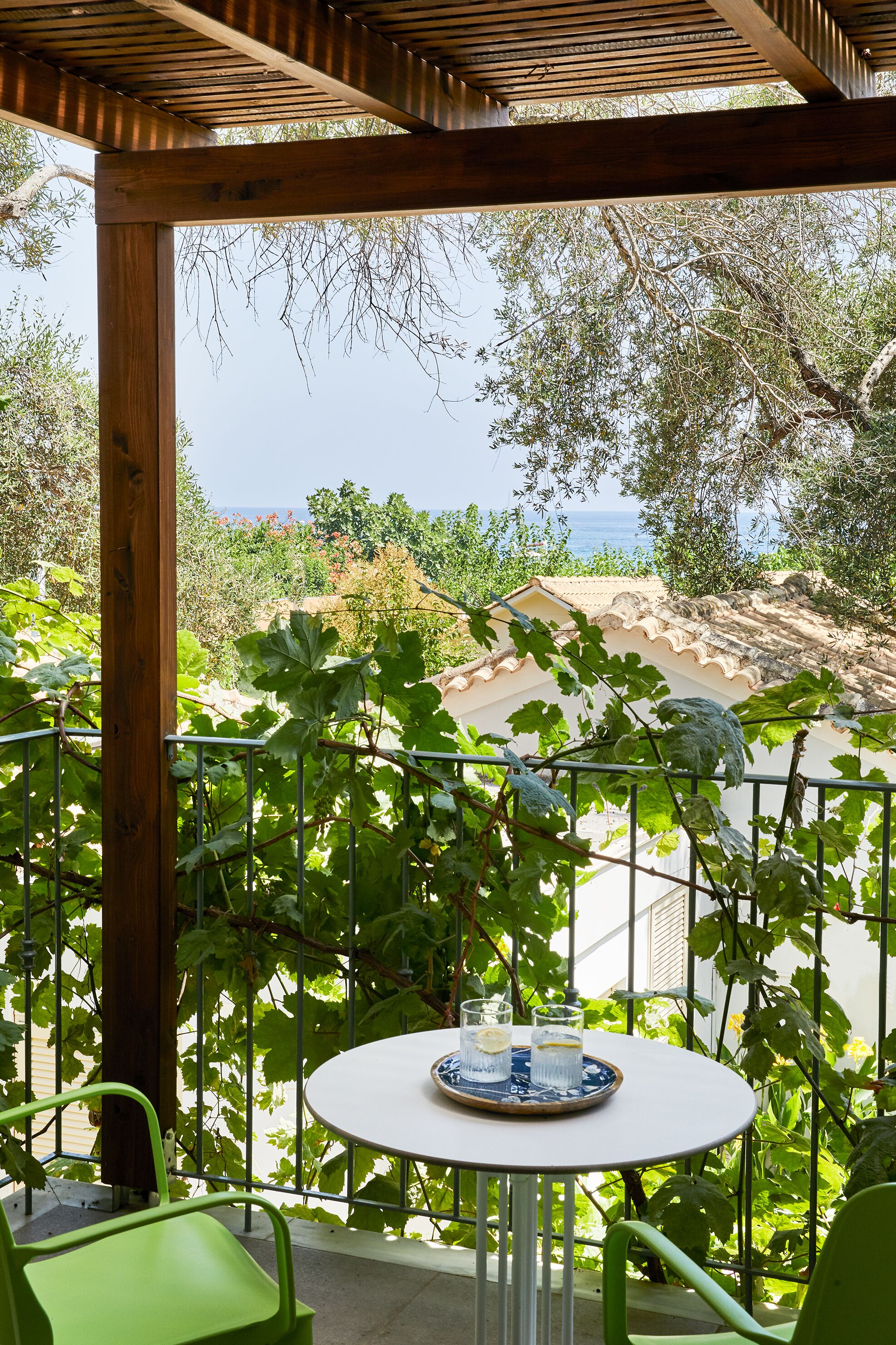 Un espace extérieur abrité, avec une table et des chaises, offrant une vue panoramique sur la mer et la verdure.