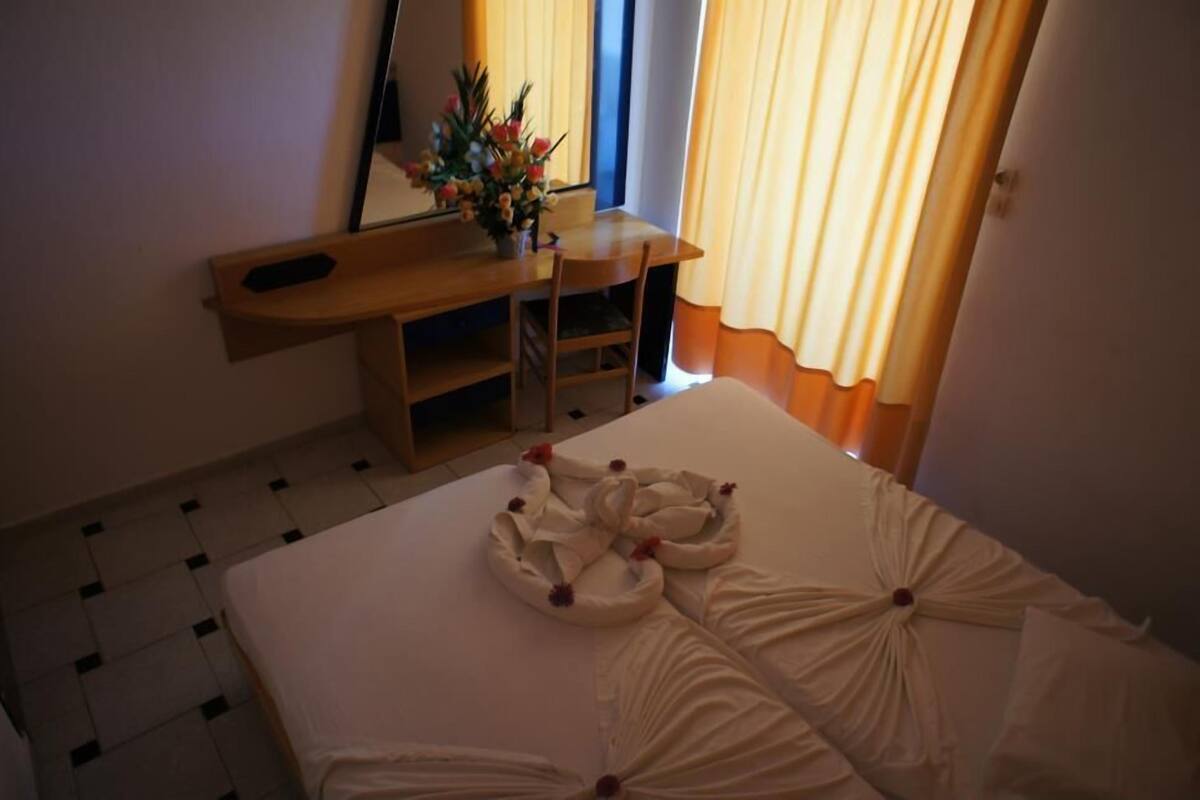 A hotel room with a bed, a desk, and a mirror.