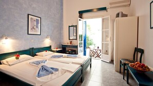 Une chambre d’hôtel avec deux lits, un bureau, une chaise et une table à manger avec des fruits.
