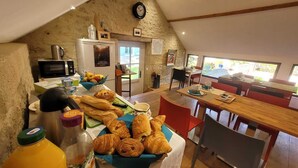 A cozy kitchen with a stone wall, a refrigerator, a microwave, and a dining area with a table and chairs. - La Cuvellerie (Narcy)