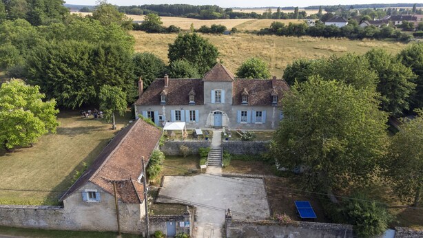 A large, historic house with a central courtyard, surrounded by lush greenery and fields. - La Cuvellerie (Narcy)