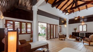A spacious living area with wicker furniture, a television, and a ceiling fan. - Baan Khunying – Secluded Phuket Beachfront Villa (Rawai)