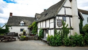 A traditional half-timbered building with a sign for 'Fleece Inn' and 'Mitchells & Butlers ales'.