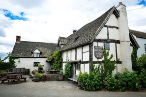 Un edificio tradicional de entramado de madera con un letrero que dice 'Fleece Inn' y 'Mitchells & Butlers ales'.