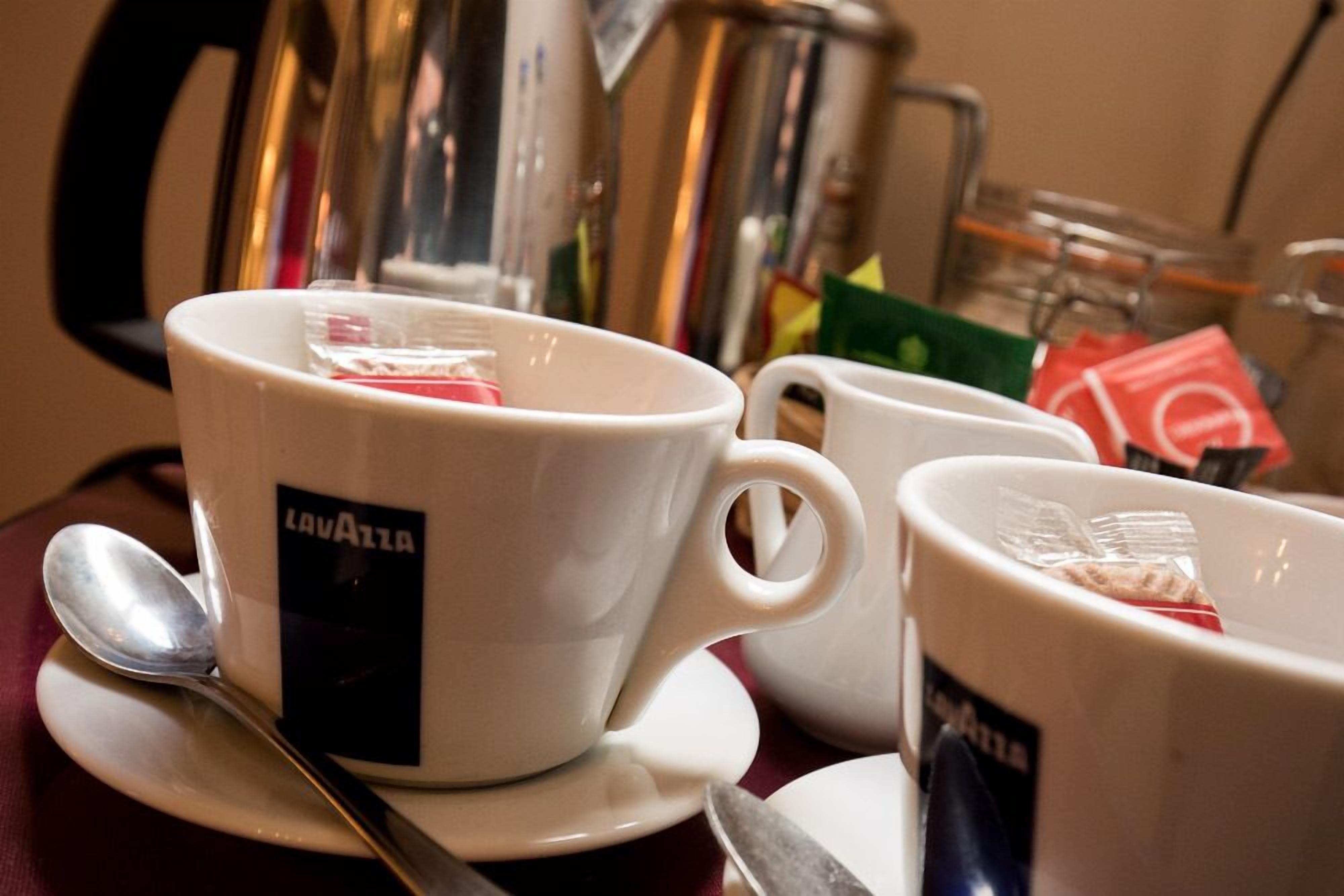 Une table avec deux tasses blanches portant l’inscription « Lavazza » et une cuillère sur une soucoupe.