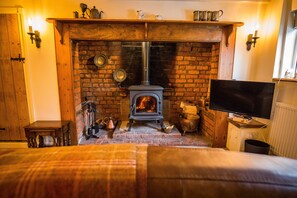 A cozy room with a brick fireplace, a television, and a bed.