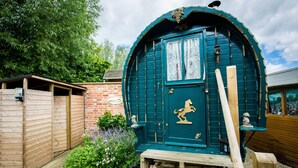 Una cabaña de madera tradicional con una puerta verde, un emblema de caballo y un banco afuera.