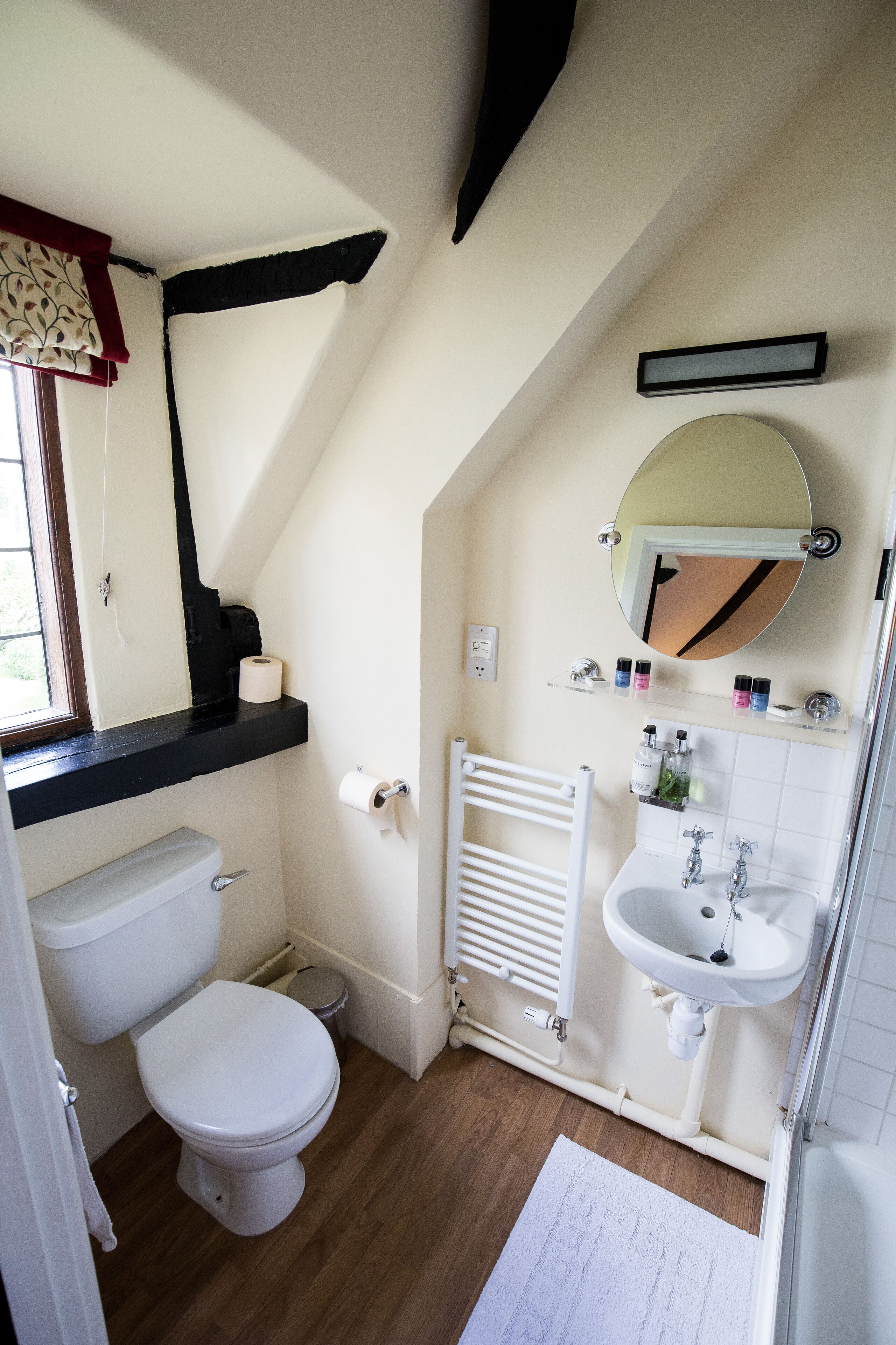 A small, compact bathroom with a toilet, sink, and mirror.