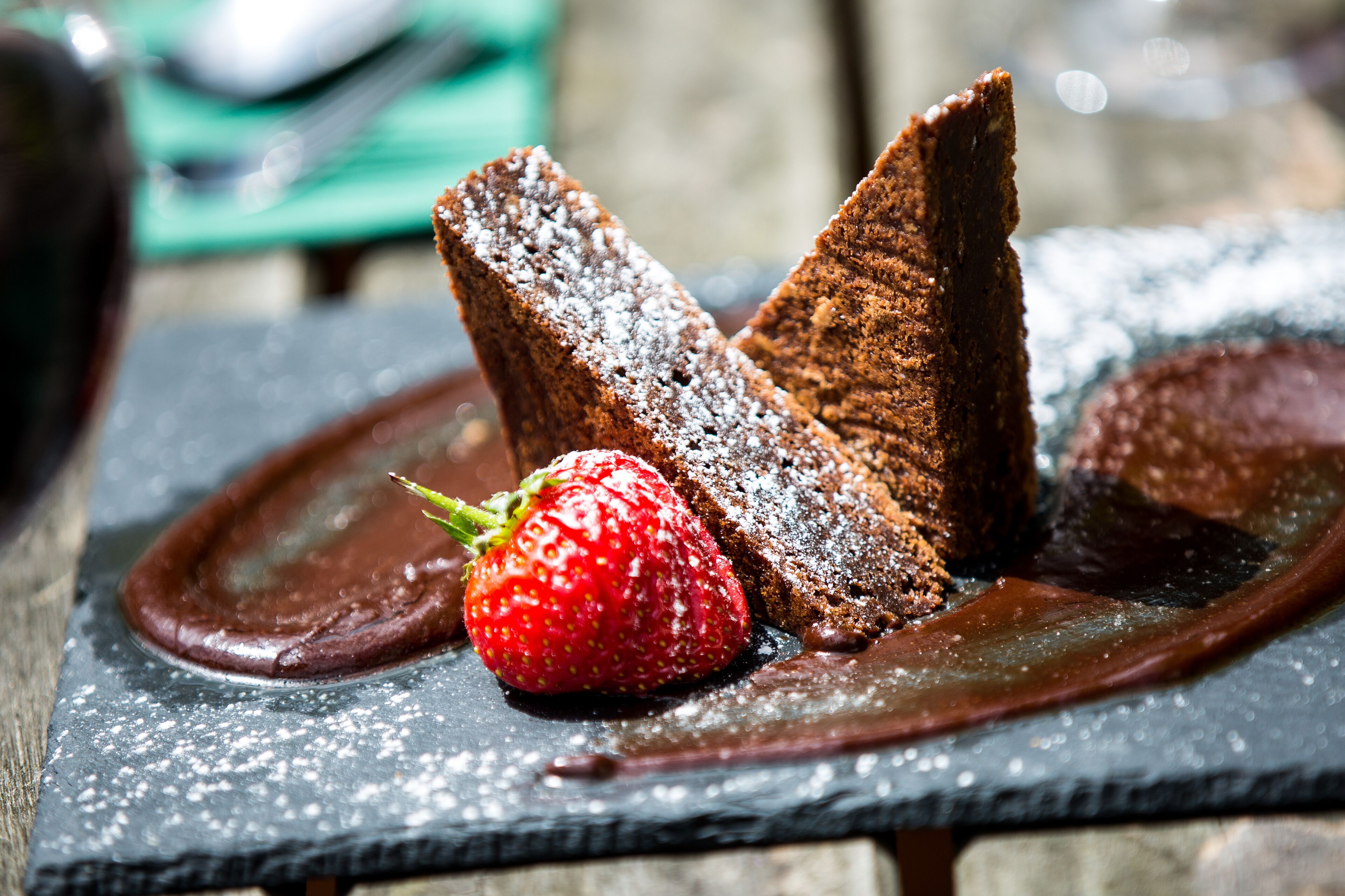 A dessert plate with a chocolate cake, a strawberry, and chocolate sauce.
