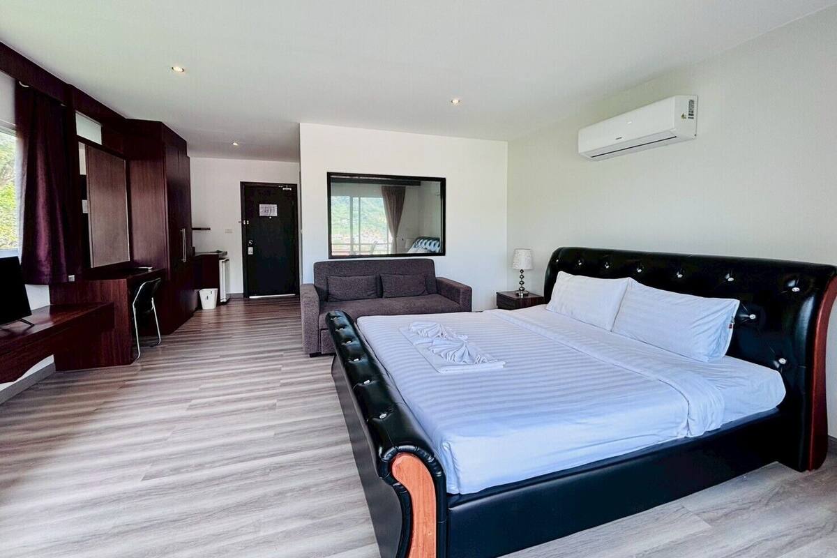 A modern hotel room with a large bed, a desk, and a sofa.