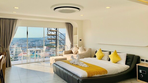 Ein modernes Hotelzimmer mit einem großen Bett, Blick auf die Stadt und einem Balkon mit einer Wendeltreppe.