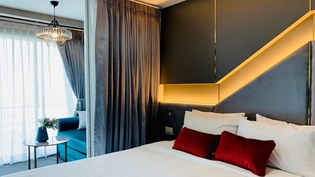 Una habitación de hotel moderna con una cama grande, una zona de estar con un sofá azul y una escalera.