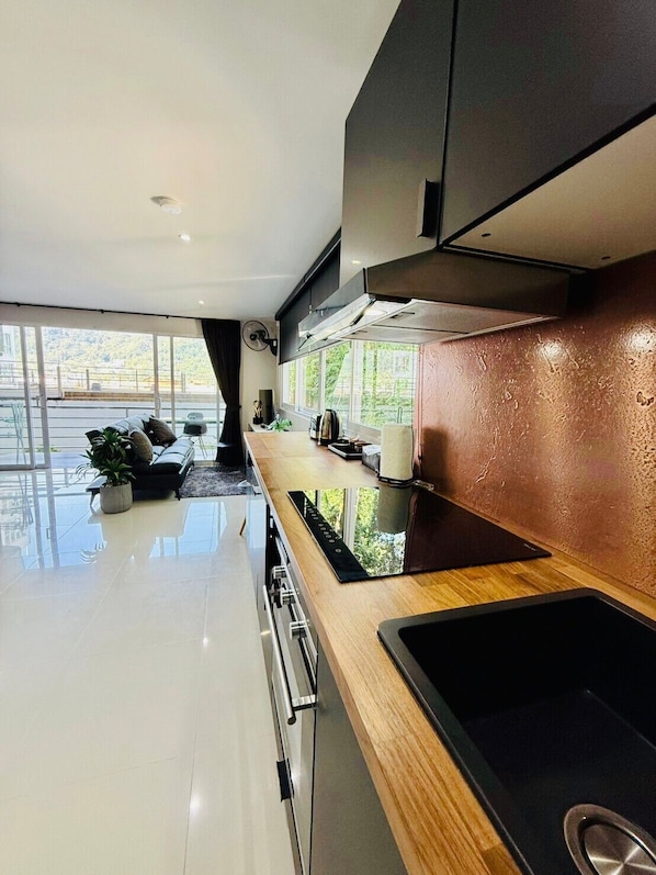 A modern kitchen with a large window, a built-in stove, and a wooden countertop. - Ocean View Treasure Residence (Patong)