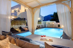 Una piscina al aire libre, sombrillas, sillones reclinables de piscina