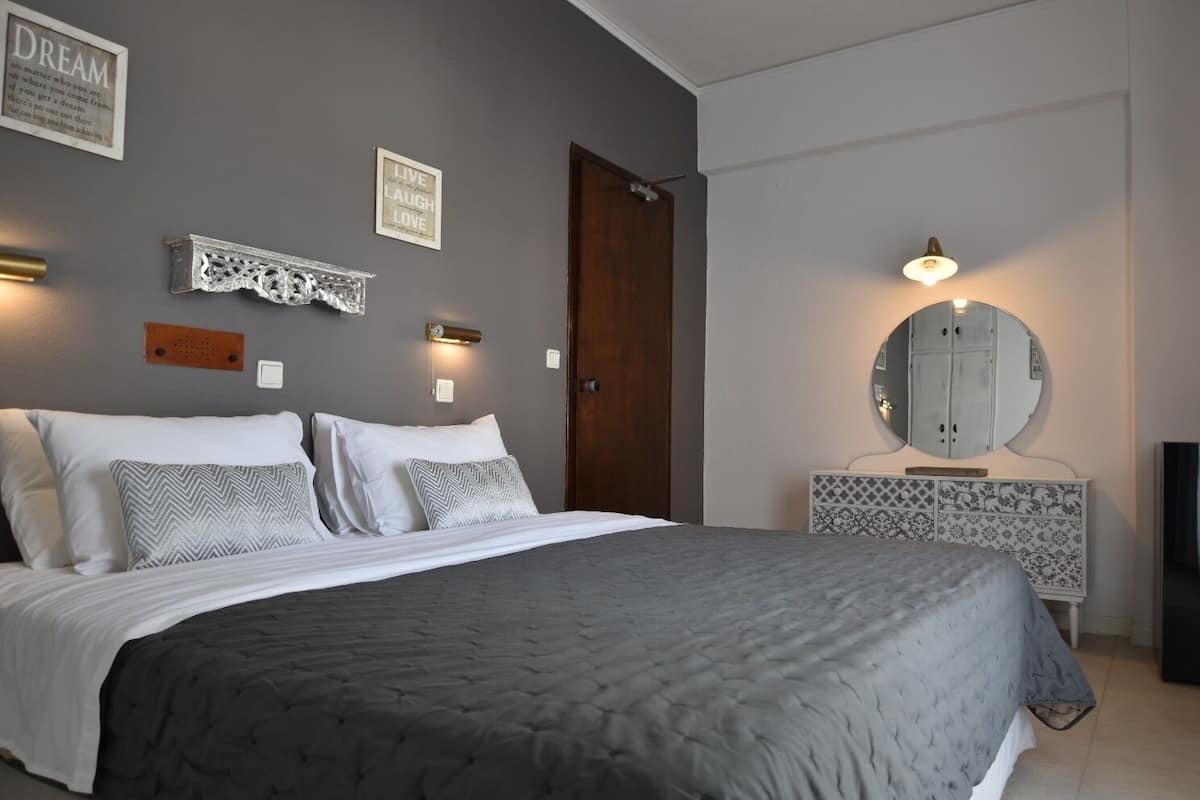A bedroom with a bed, a dresser with a mirror, and two wall-mounted light fixtures.