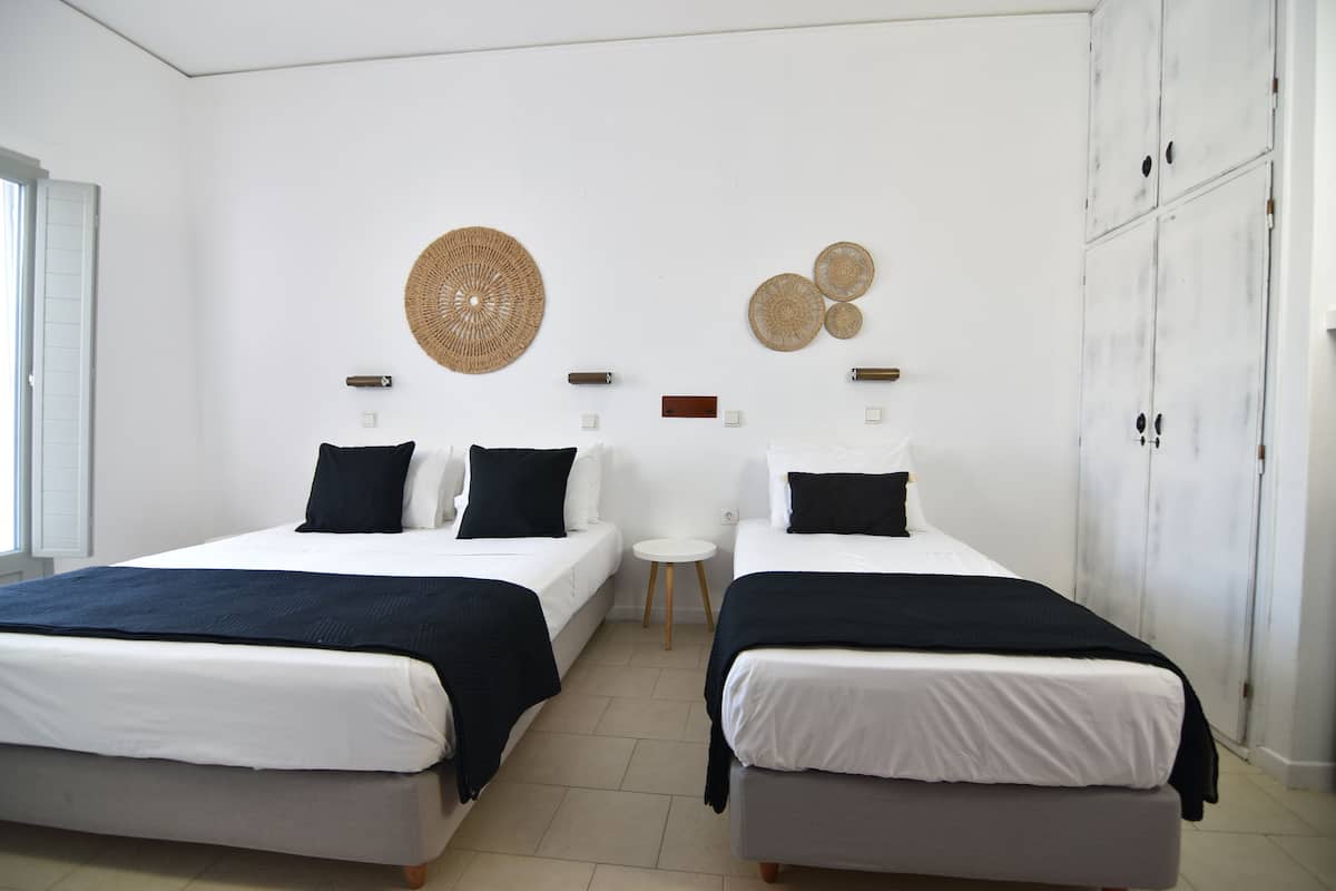 A room with two beds, a small round table, and a wall with decorative items.