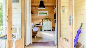 Interior de una cabaña de madera con una cama, escritorio y un cuadro en la pared.