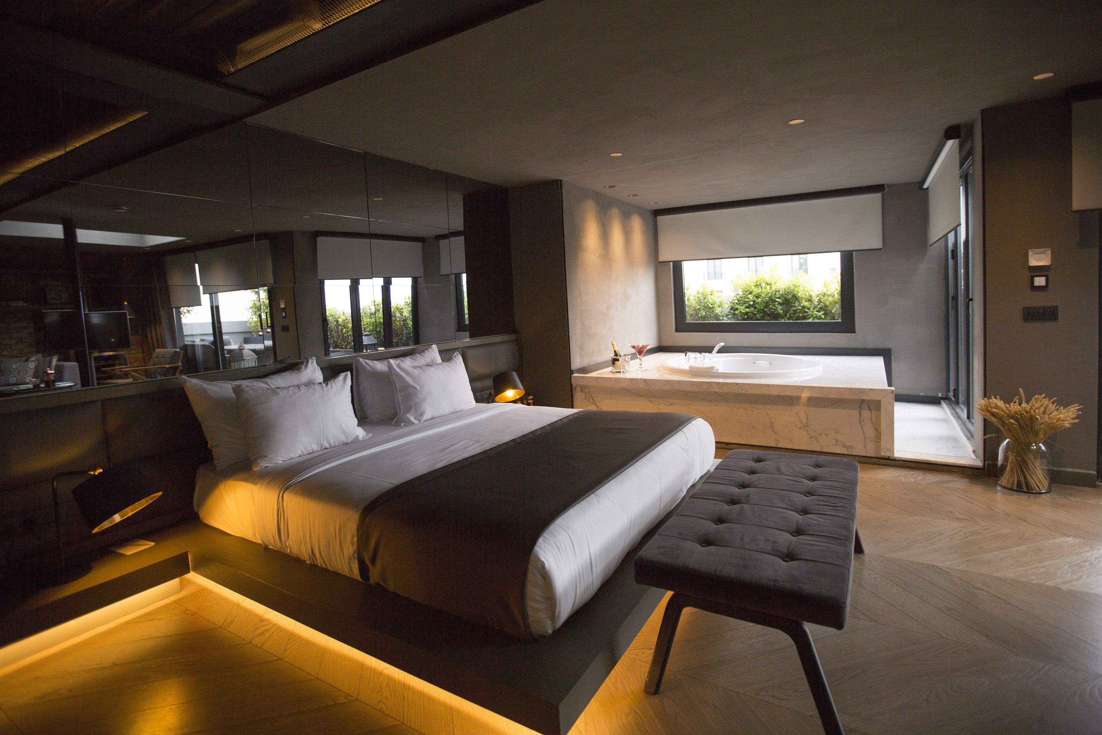 A modern bedroom with a large bed, a separate sitting area, and a view of the outdoors.