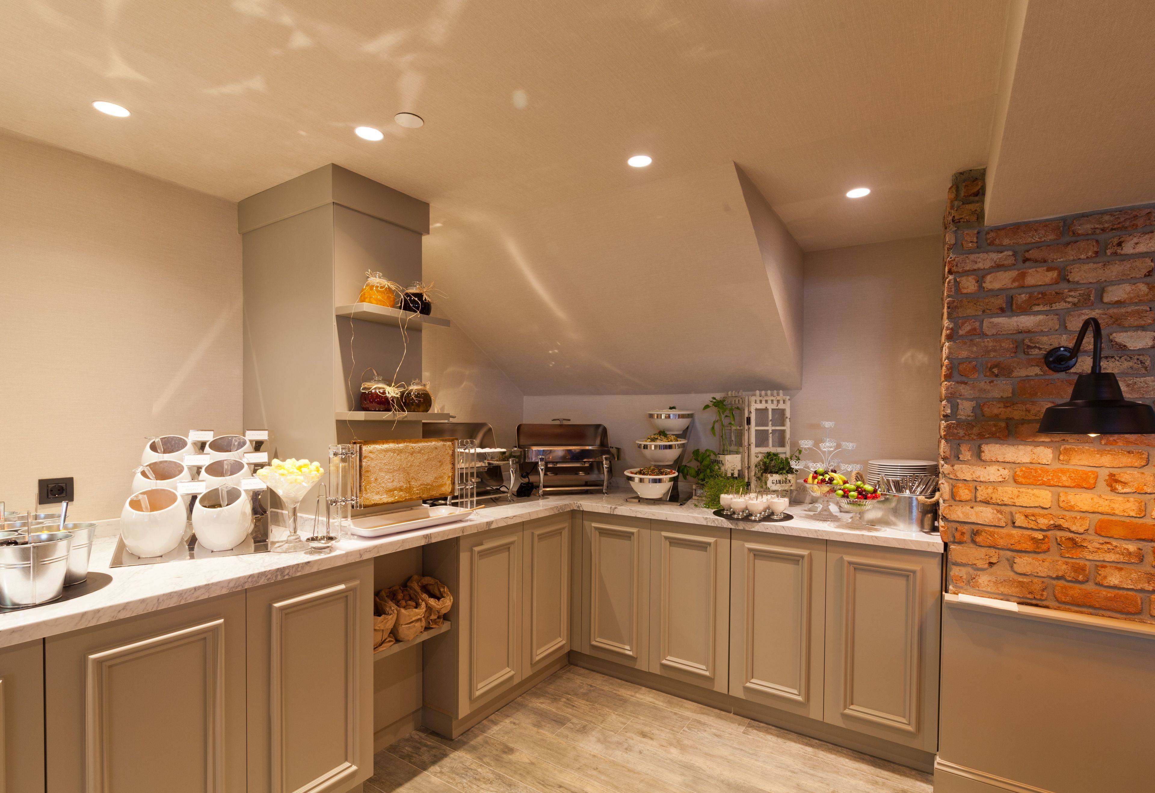 Une cuisine moderne dotée d’un plan de travail en marbre, de meubles encastrés et d’un mur décoratif en briques.