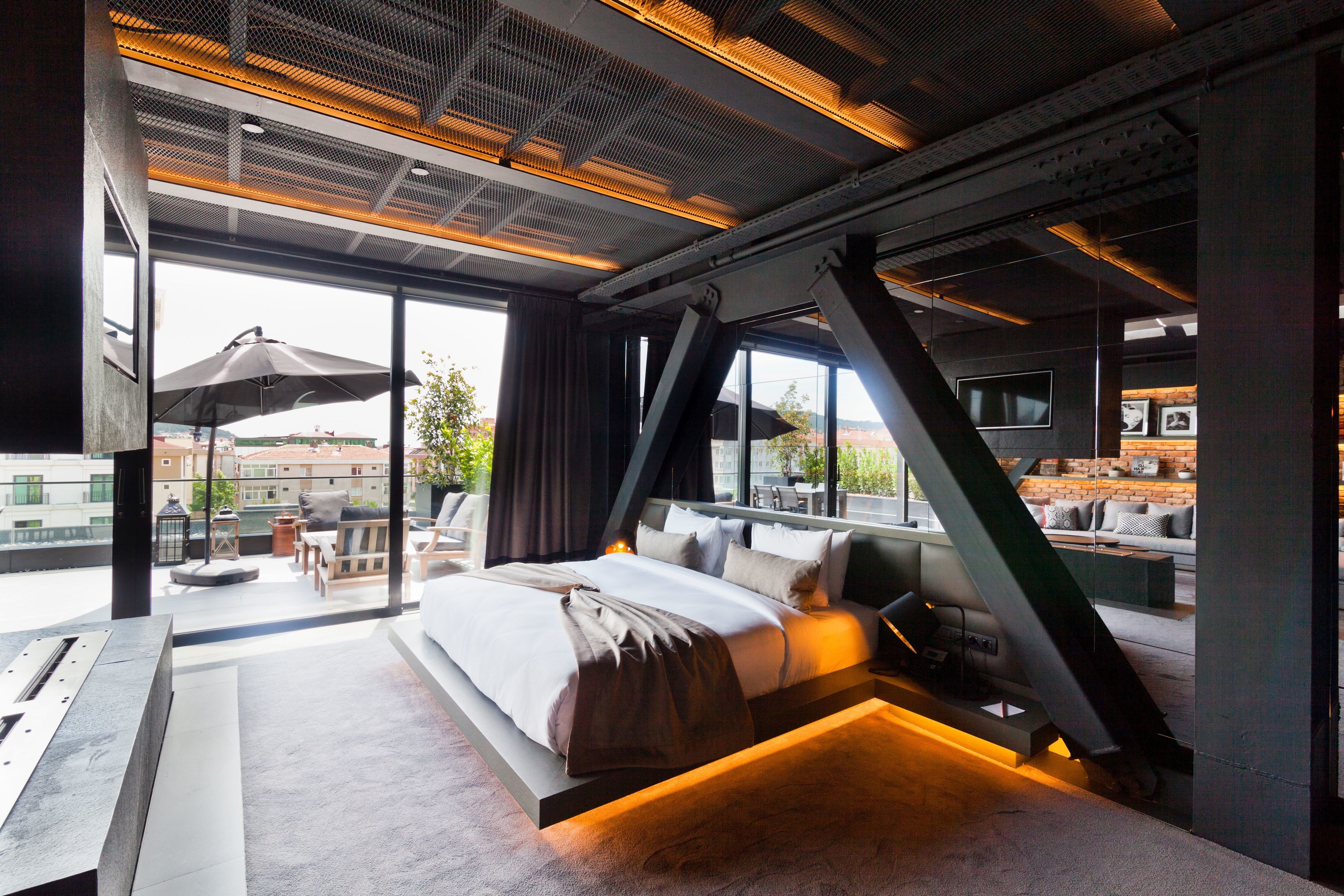 A modern bedroom with a large bed, a view of the city, and a unique architectural design.