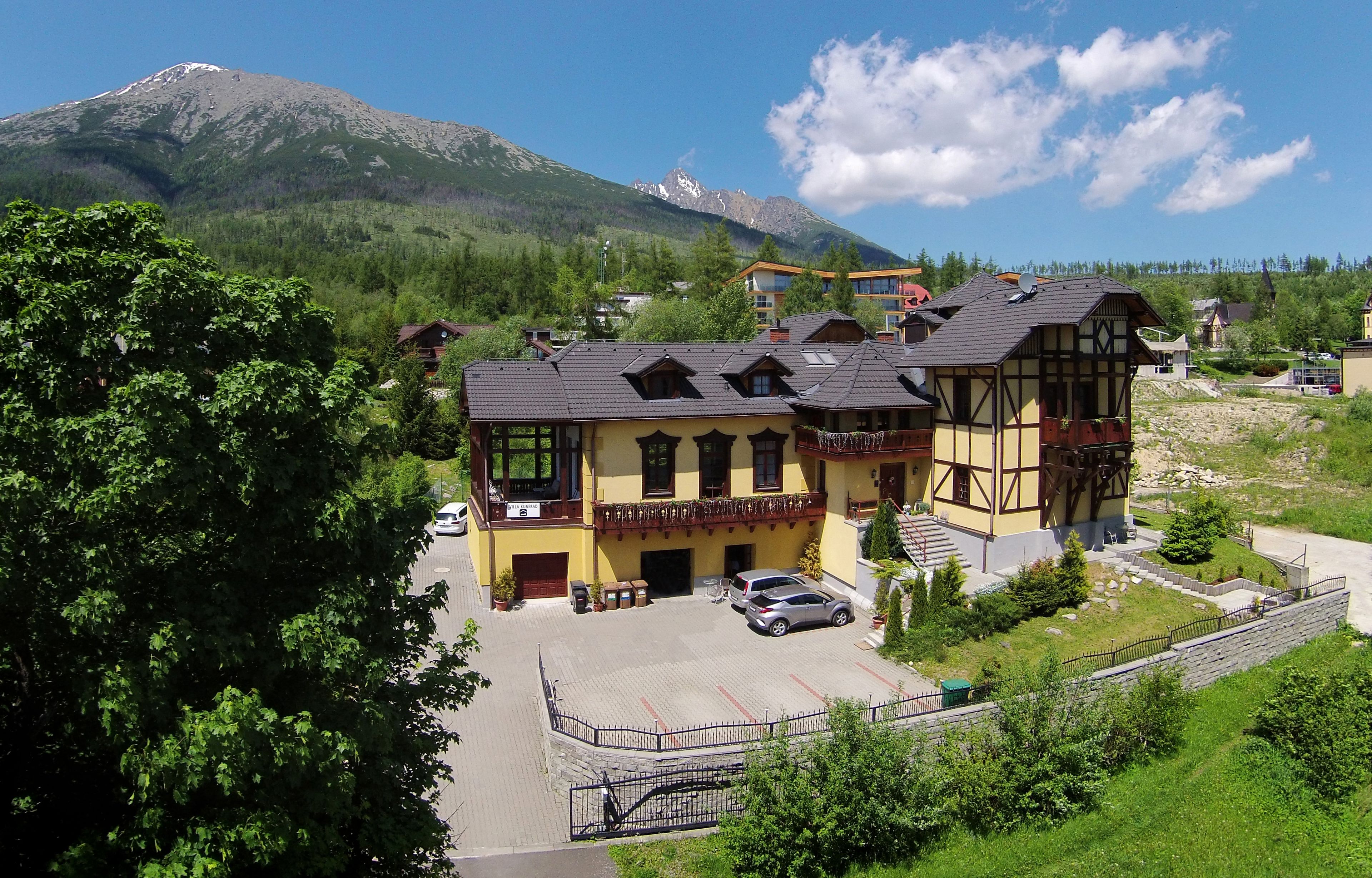 Un edificio in stile chalet tradizionale, con tetto spiovente, un balcone e un’area di parcheggio.