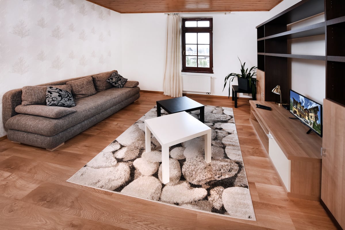 Ein modernes Wohnzimmer mit einer Couch, einem Couchtisch und einem Fernseher auf einer Holzkommode.