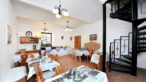 A dining area with multiple tables, chairs, and a staircase. - Villa Kunerad (Vysoké Tatry)