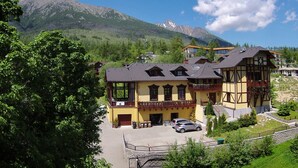 A two-story building with a balcony, a car parked in front, and a mountain in the background. - Villa Kunerad (Vysoké Tatry)