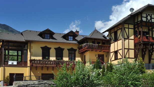A traditional chalet with a balcony, a sign indicating 'Villa Kunerad', and a mountain backdrop. - Villa Kunerad (Vysoké Tatry)