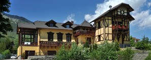 A traditional chalet with a balcony, a sign indicating 'Villa Kunerad', and a mountain backdrop. - Villa Kunerad (Vysoké Tatry)