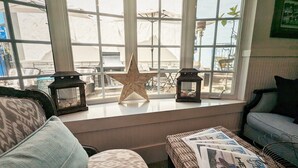 A cozy seating area with a star decoration, two lanterns, and a wicker table with magazines. - Capitola Hotel (Capitola)