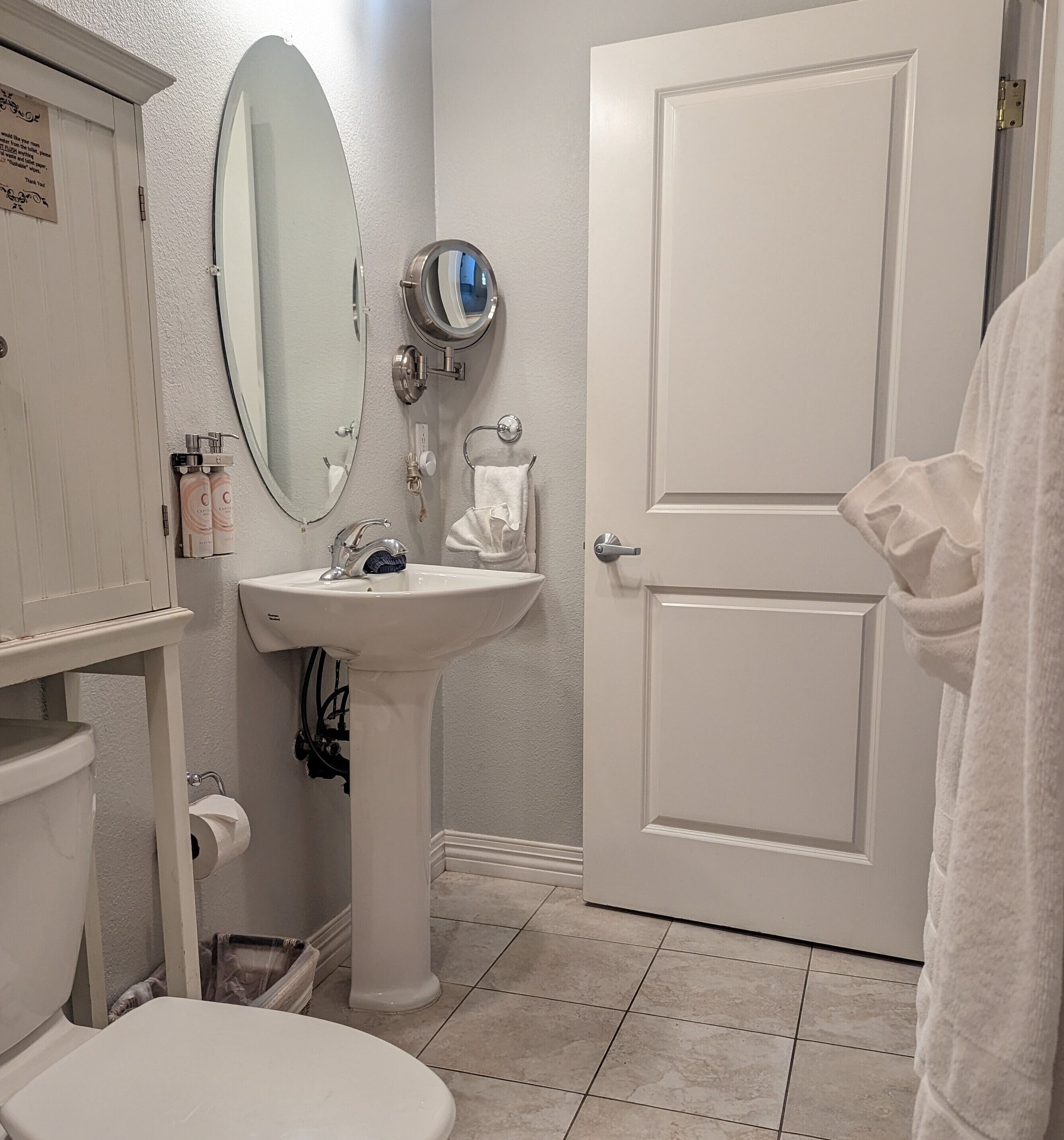 A bathroom with a toilet, sink, mirror, and a door.