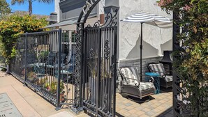 A hotel entrance with a wrought iron gate, outdoor seating area with striped cushions, and a sign reading "Capitol Hotel". - Capitola Hotel (Capitola)