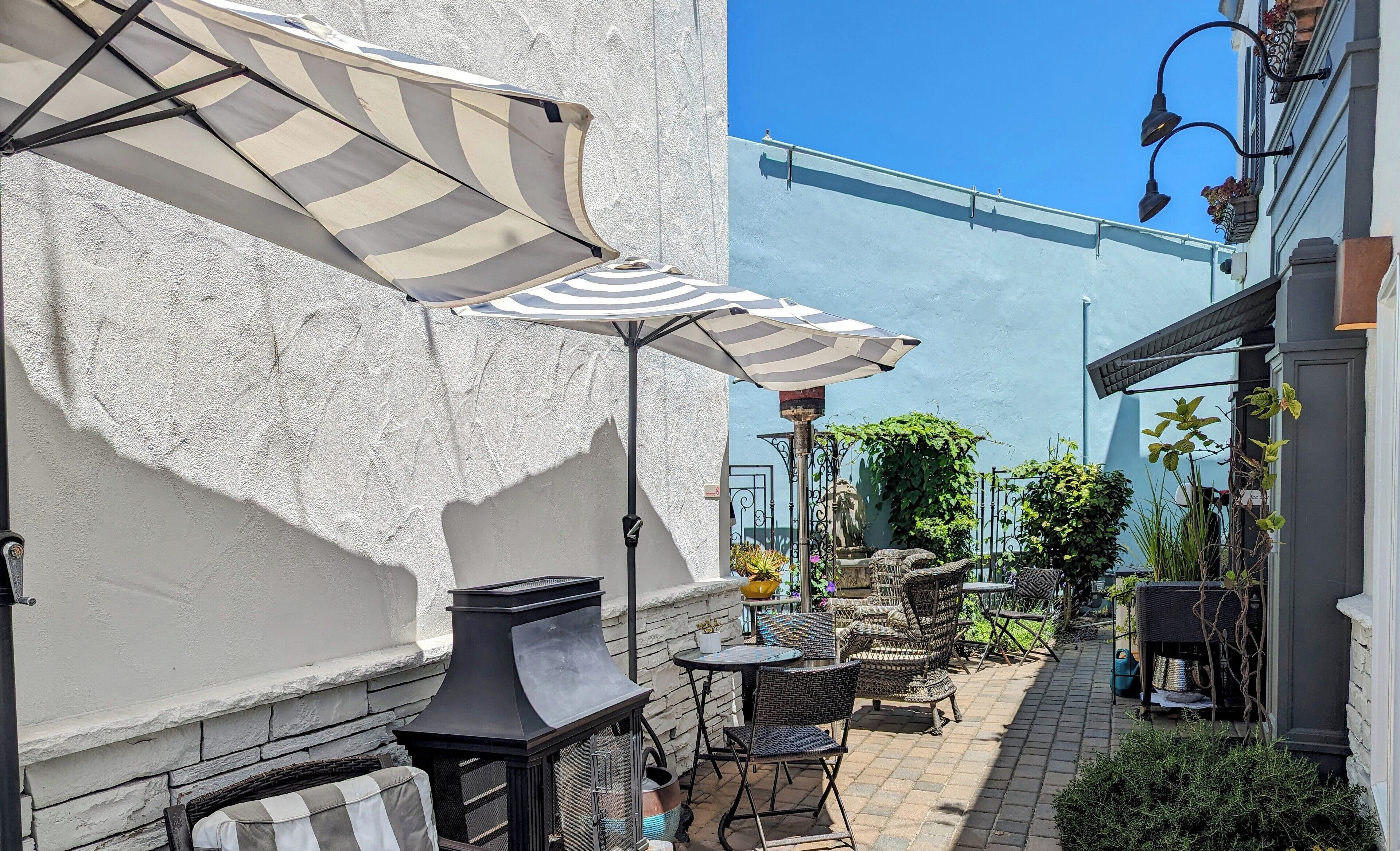 Un patio con mobiliario exterior, una parrilla y sombrillas.