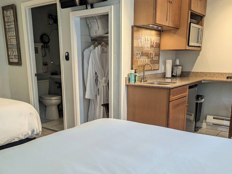 A bedroom with two beds, a bathroom with a toilet and sink, and a kitchenette with wooden cabinets and a countertop.