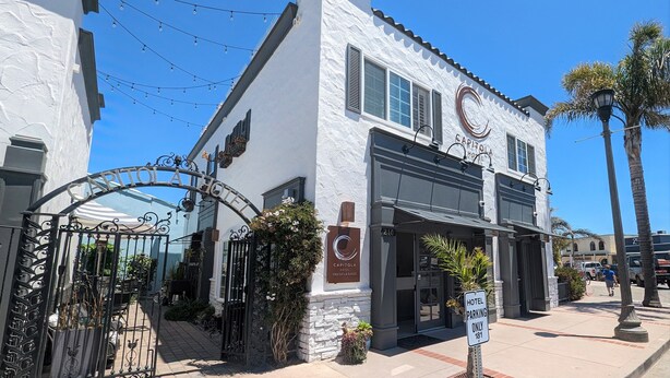 A hotel entrance with a gated driveway, a sign indicating parking is only for hotel guests, and a clear blue sky above. - Capitola Hotel (Capitola)
